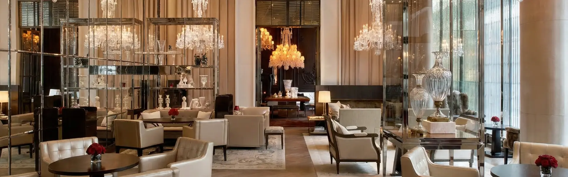 Architecte d'intérieur hôtellerie de luxe : lobby avec lustres en cristal, fauteuils crème et étagères miroir.