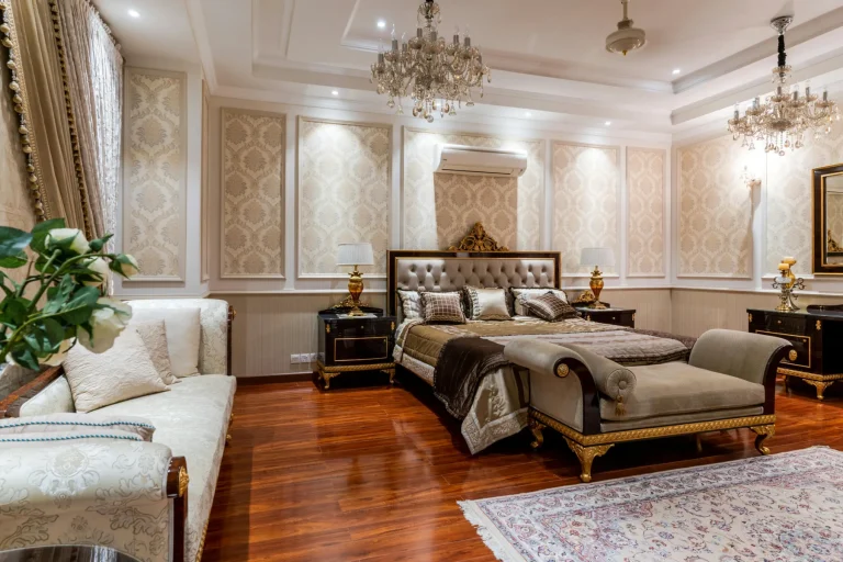Chambre de luxe baroque avec lit capitonné doré, papier peint damassé, lustres en cristal et parquet en bois rouge.